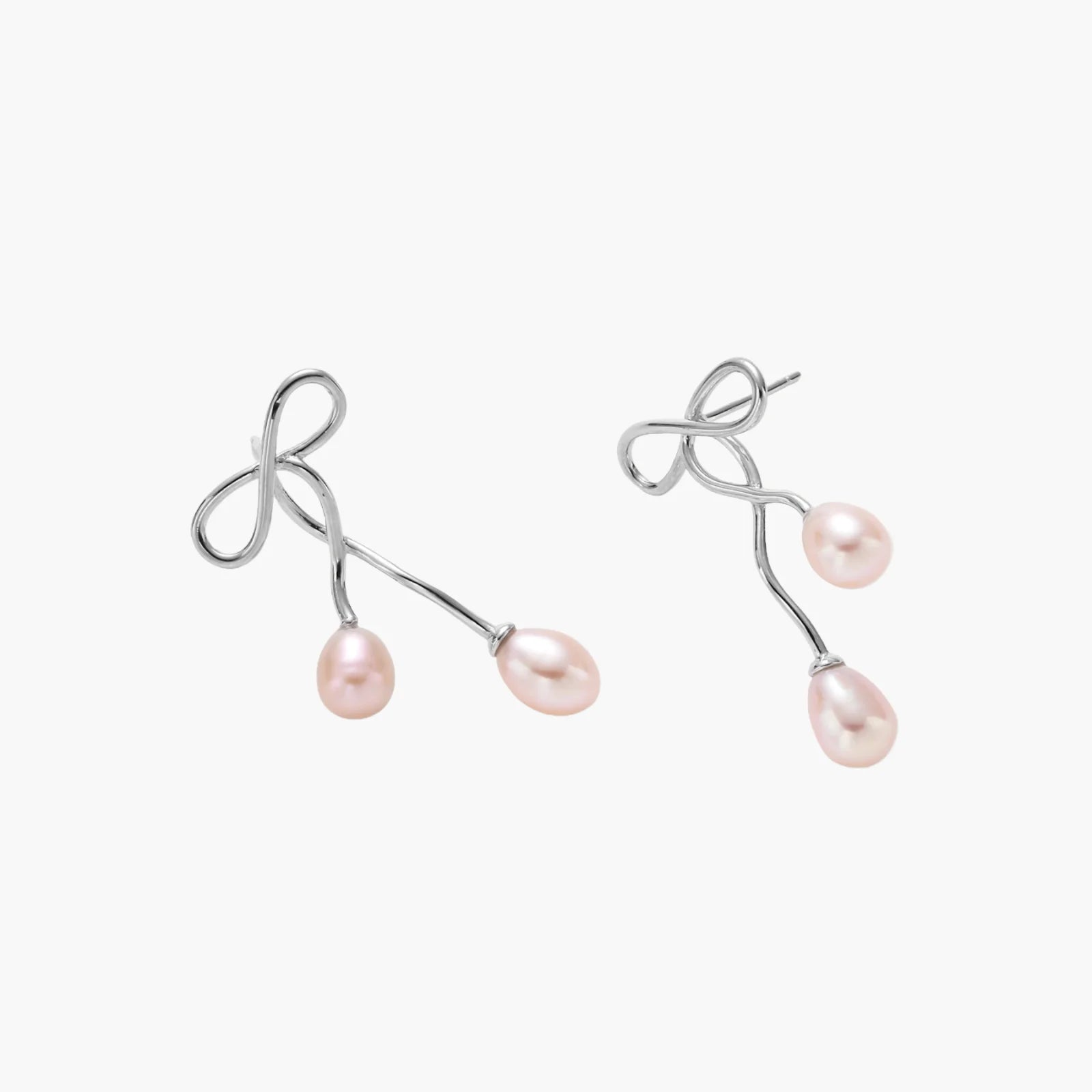 Rhodium-plated silver earrings with organic vine curves and two peachy freshwater pearls on cream background