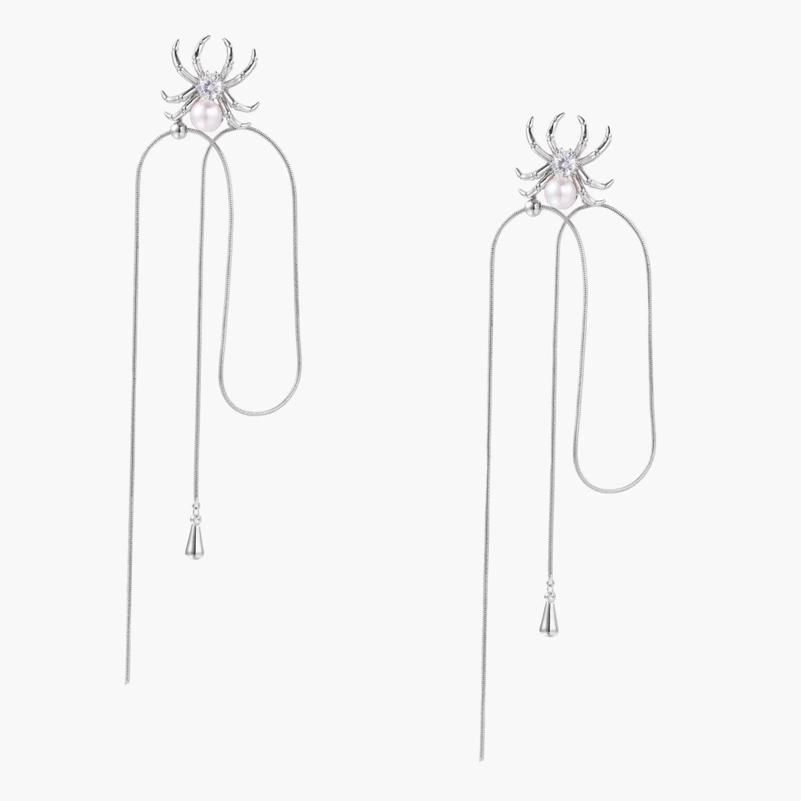 White gold plated spider earrings with pearl body and long threader chains on beige background