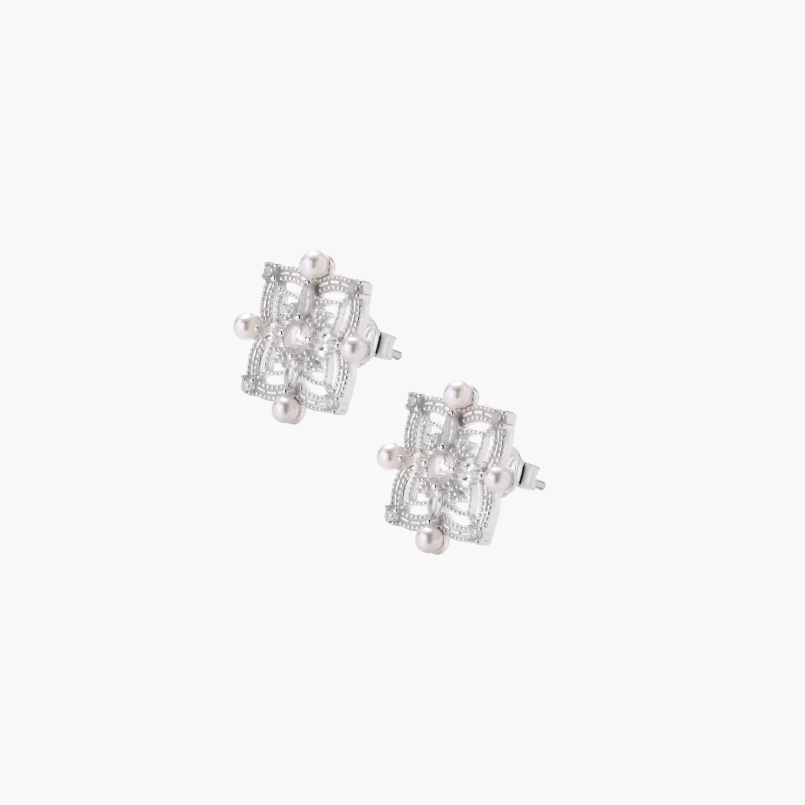 Ornate sterling silver stud earrings with mandala-inspired filigree pattern and four freshwater pearls on beige background