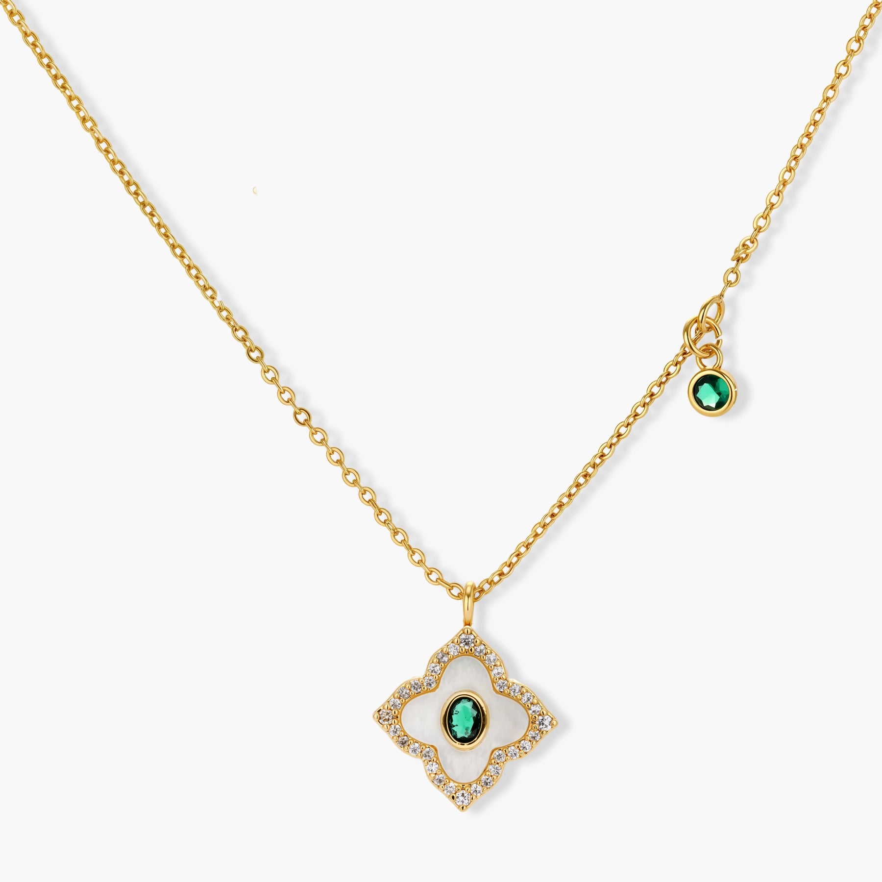 Gold-plated quatrefoil pendant and earrings with white enamel, emerald CZ center stones, and crystal borders on white background.