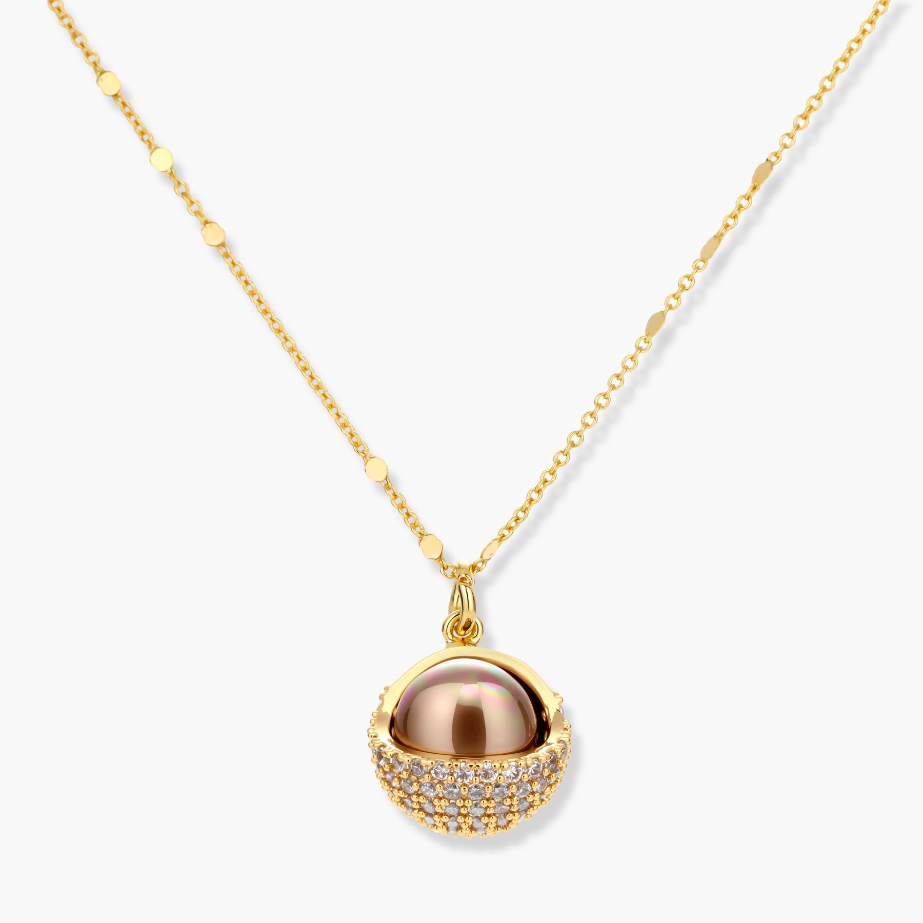 Elegant spherical pendant necklace and earrings set featuring crystal-pavé bottom half in gold or silver finish on white background.