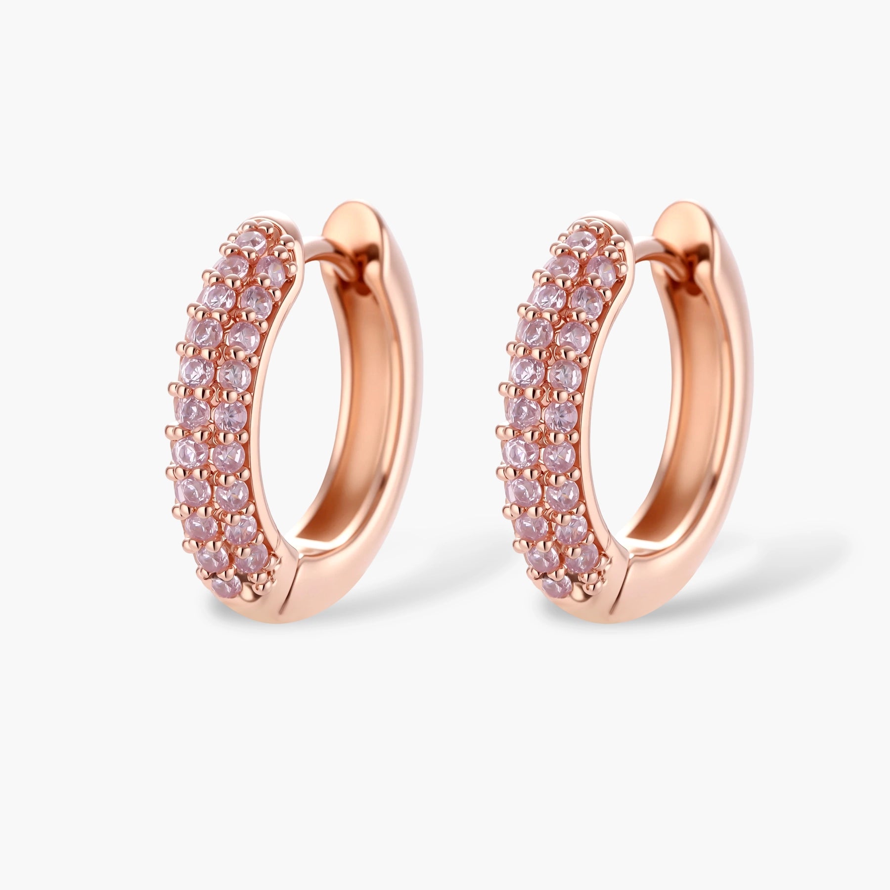 Rose gold jewelry set with pavé cubic zirconia stones including curved necklace, hoop earrings, and adjustable ring on cream background.