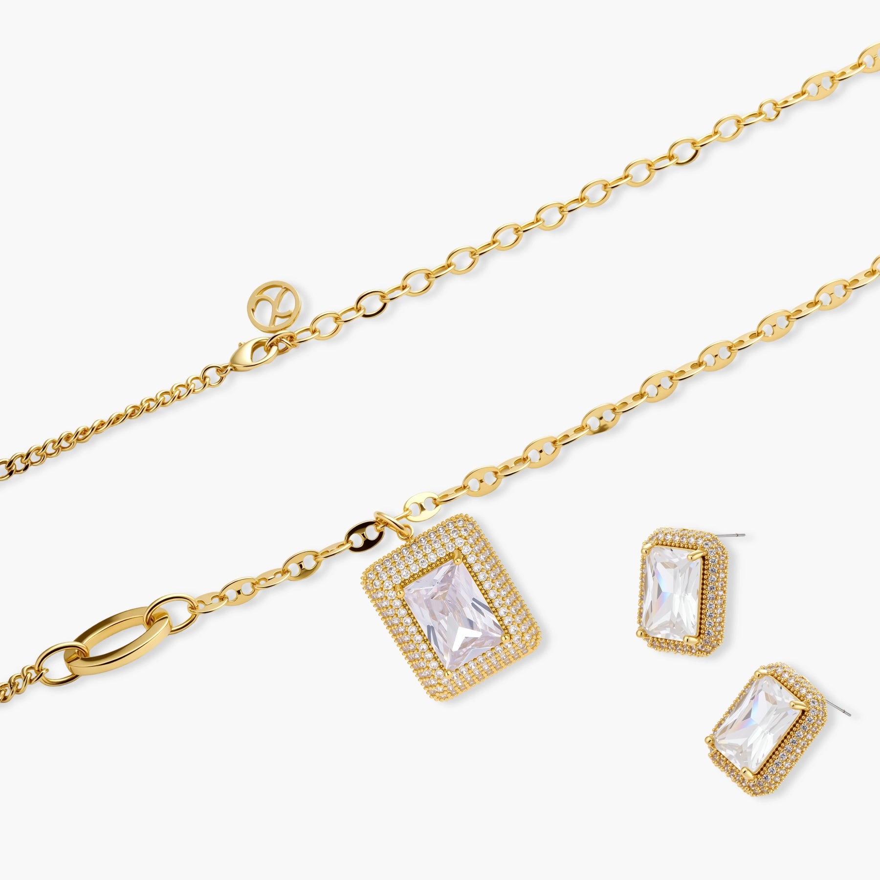 Gold-plated jewelry set with rectangular cubic zirconia stones in pave halo settings on cream background