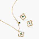 Gold-plated quatrefoil pendant and earrings with white enamel, emerald CZ center stones, and crystal borders on white background.