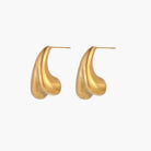 Pair of sculptural gold stud earrings with twisted organic forms on cream background