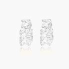 White gold plated sculptural hoop earrings with organic wavy edges and reflective metallic finish on cream background