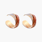 Sculptural gold-plated hoop earrings with diagonal purple and coral enamel stripes in twisted ribbon design