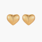 Gold heart-shaped stud earrings with parallel ridged texture on cream background
