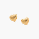 Gold heart-shaped stud earrings with parallel ridged texture on cream background