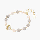 Bracelet with cloudy quartz beads, freshwater pearls, and gold-wrapped baroque pearl centerpiece on white background.