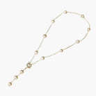 Gold-plated lariat necklace with baroque pearls and textured caps on cream background, showing adjustable Y-shaped design.