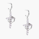 White gold-plated hoop earrings with sparkling zirconia cross charms dangling against cream background