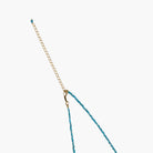 Delicate gold vermeil necklace with teal apatite beads and freshwater pearl on white background.