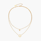 Gold layered necklace set with sunburst and smiley face pendants on delicate chains against white background.