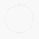 Delicate sterling silver chain necklace with small freshwater pearls arranged in a curved smile arc on cream background.