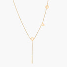 Gold Y-shaped necklace with L-O-V-E letter charms and vertical bar pendant on delicate chain against cream background