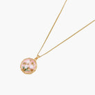 Gold pendant with pink enamel backdrop, white freshwater pearls as tulip blooms, and green leaf accents on rope chain.