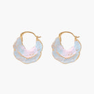 Shell-shaped hoop earrings with iridescent blue-pink enamel and gold trim on cream background