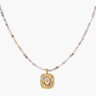 Ornate gold-plated pendant necklace with multicolored gemstone beads in purple, pink and clear tones on white background