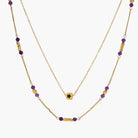 Two layered gold-tone necklaces with purple stone beads and star pendant against cream background.