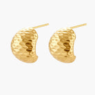 Pair of textured gold-plated sterling silver huggie earrings with dimpled surface finish on cream background.