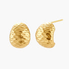 Pair of textured gold-plated sterling silver huggie earrings with dimpled surface finish on cream background.