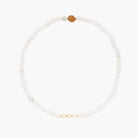 Three layered white beaded bracelets with carved orange agate lotus centerpiece and freshwater pearls on cream background.