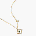 Gold-plated quatrefoil pendant and earrings with white enamel, emerald CZ center stones, and crystal borders on white background.