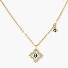 Gold-plated quatrefoil pendant and earrings with white enamel, emerald CZ center stones, and crystal borders on white background.