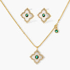 Gold-plated quatrefoil pendant and earrings with white enamel, emerald CZ center stones, and crystal borders on white background.